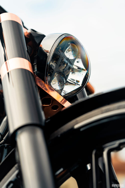 Close-up of a Harley Davidson motorcycle headlight with a shiny metallic finish.